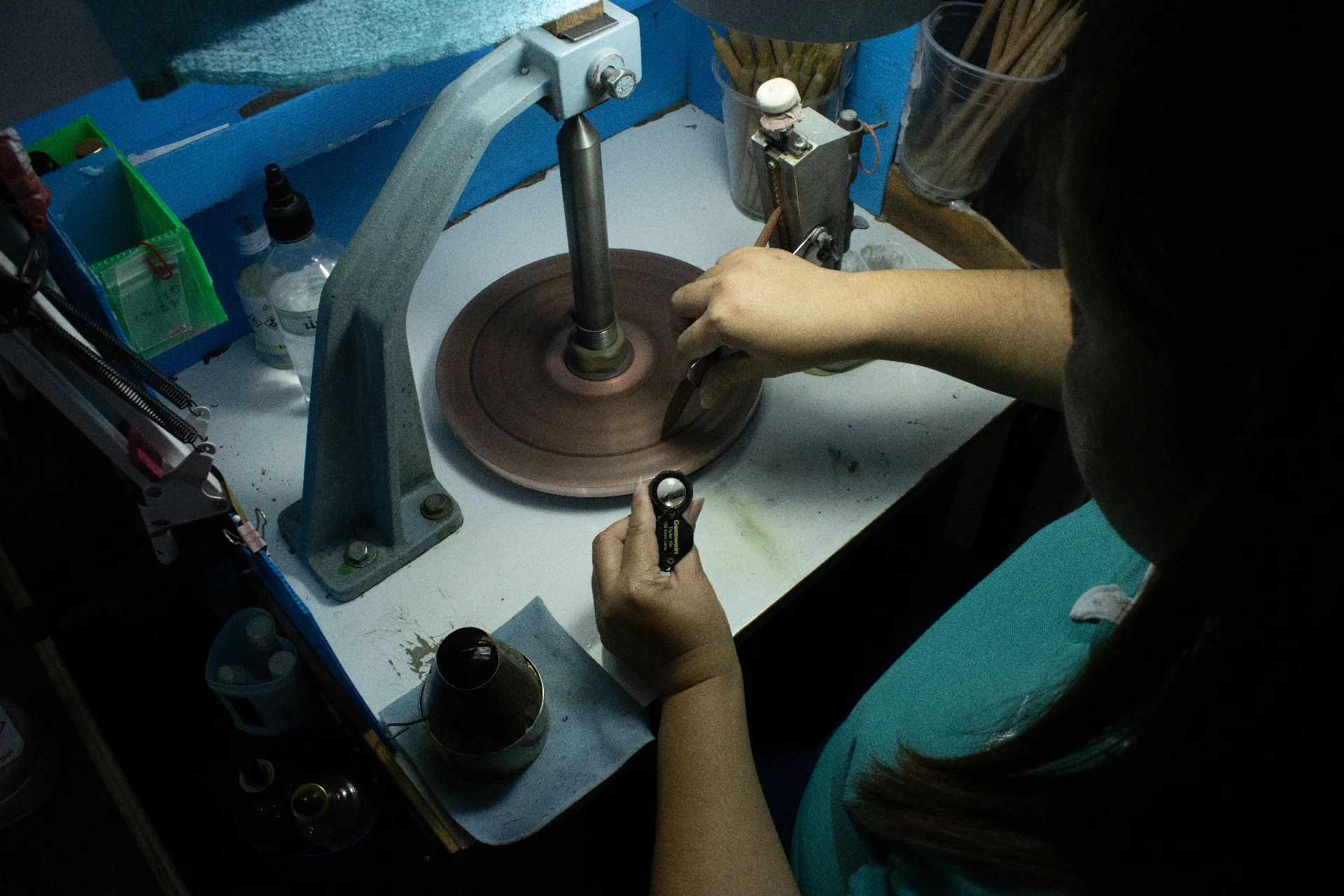 Lapidary craftsman inspecting a gemstone at the cutting wheel